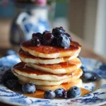 Perfecte Start: Fluffy American Pancakes met Bosbessen en Ahornsiroop.